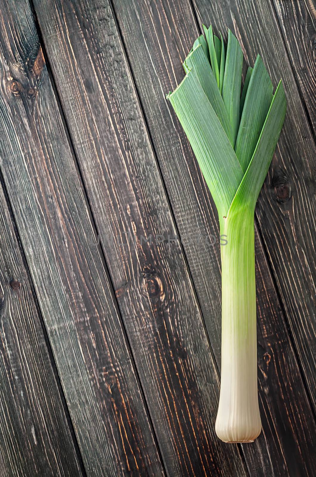 Leek on wooden background top view. Free space.