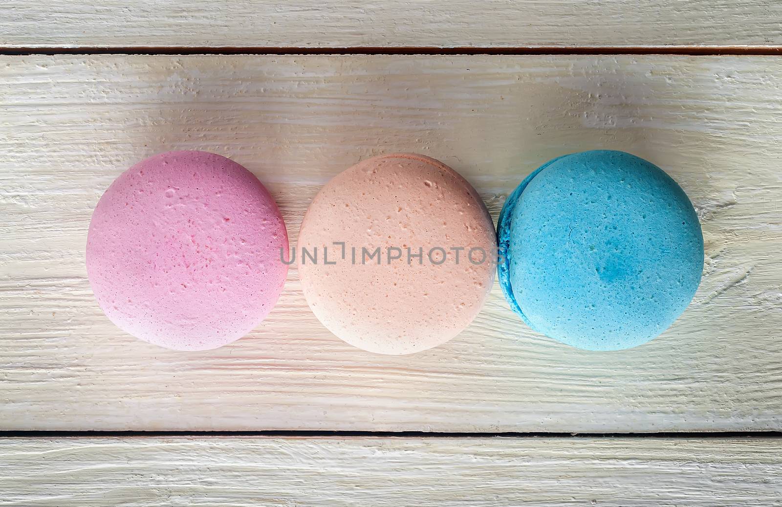Three macaroons in a row on wooden background top view