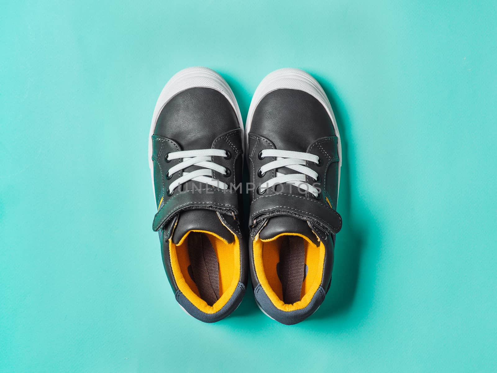 pair of new kids or adult sneakers on blue background, top view. Flat lay gray and yellow or mustard color sneakers shoes on colorful bright blue background with copy space for text or design