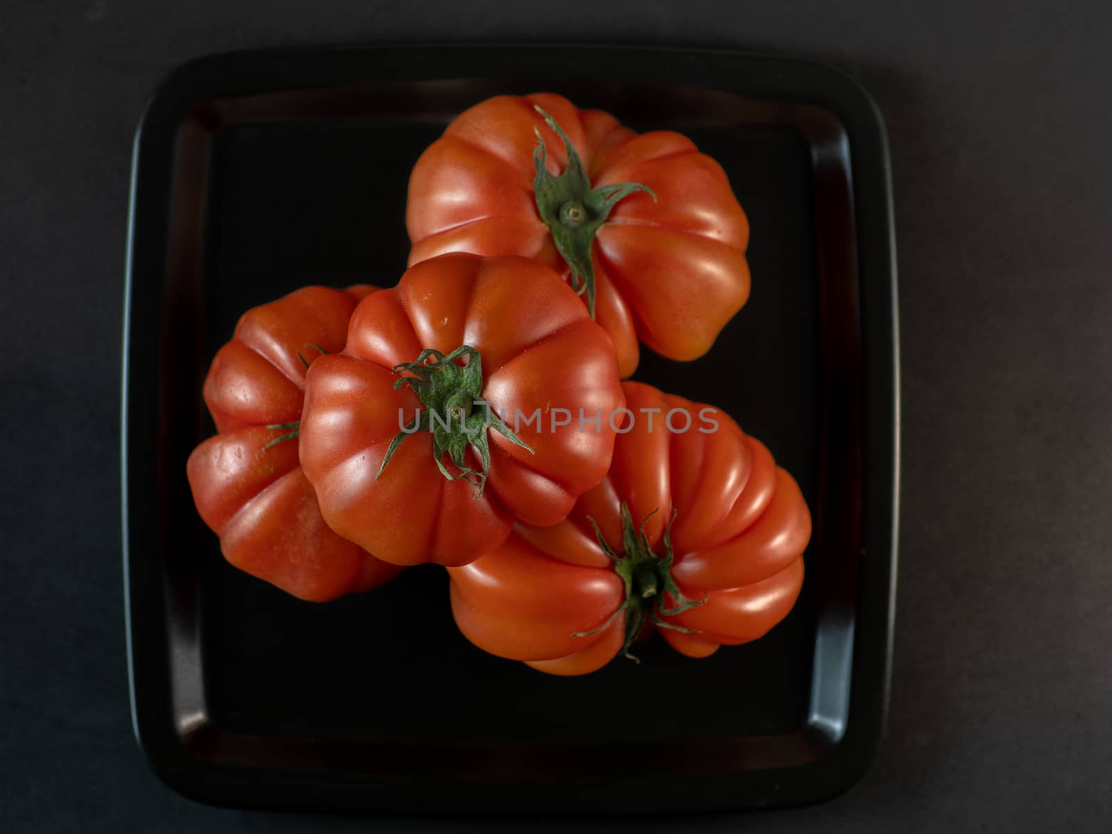 tomatoes in black plate on dark table