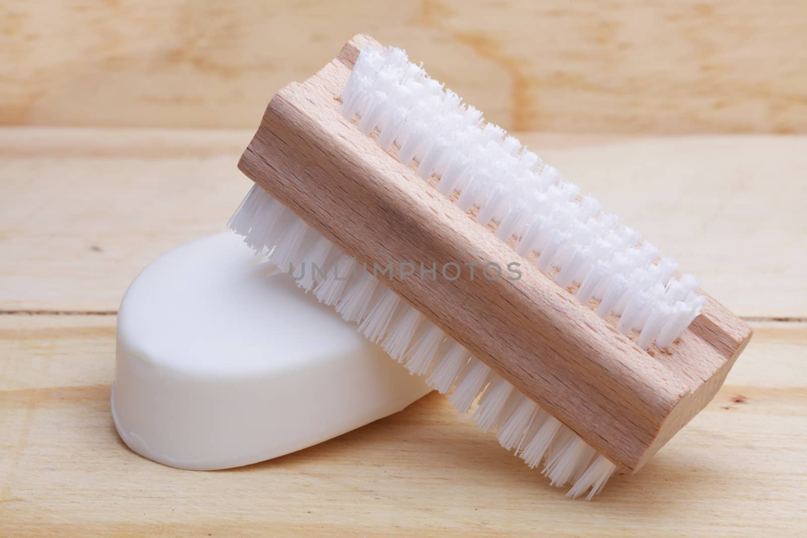 A bar of soap and nail brush on wood surface