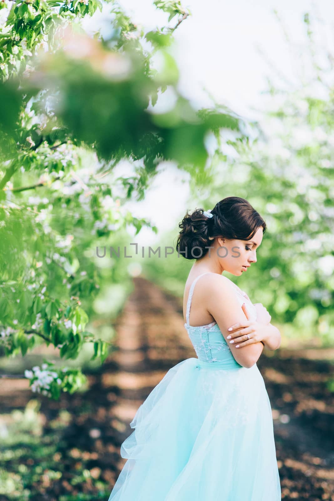 brunette girl in a turquoise dress in the spring garden by Andreua