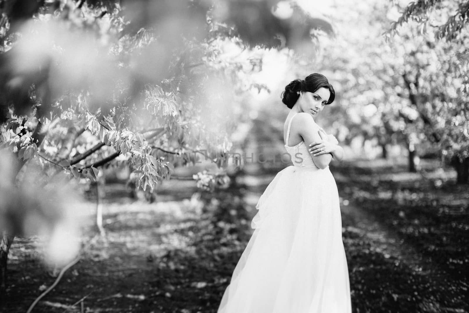 brunette girl in a turquoise dress walking in the spring garden