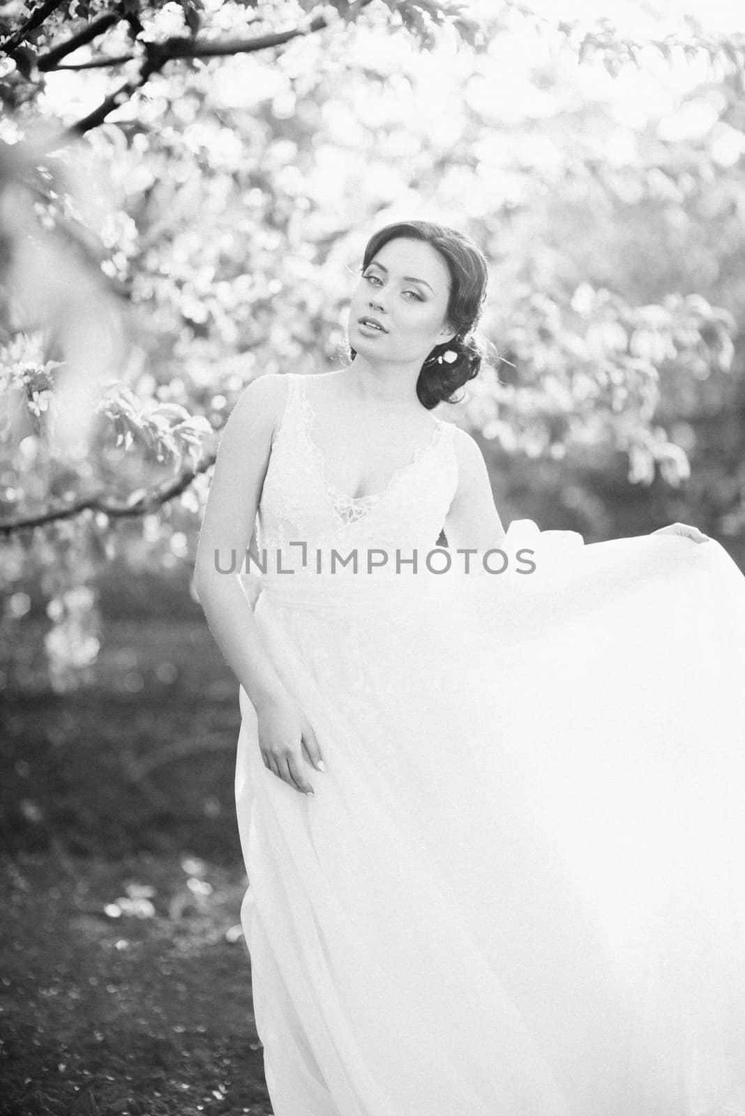 brunette girl in a turquoise dress walking in the spring garden