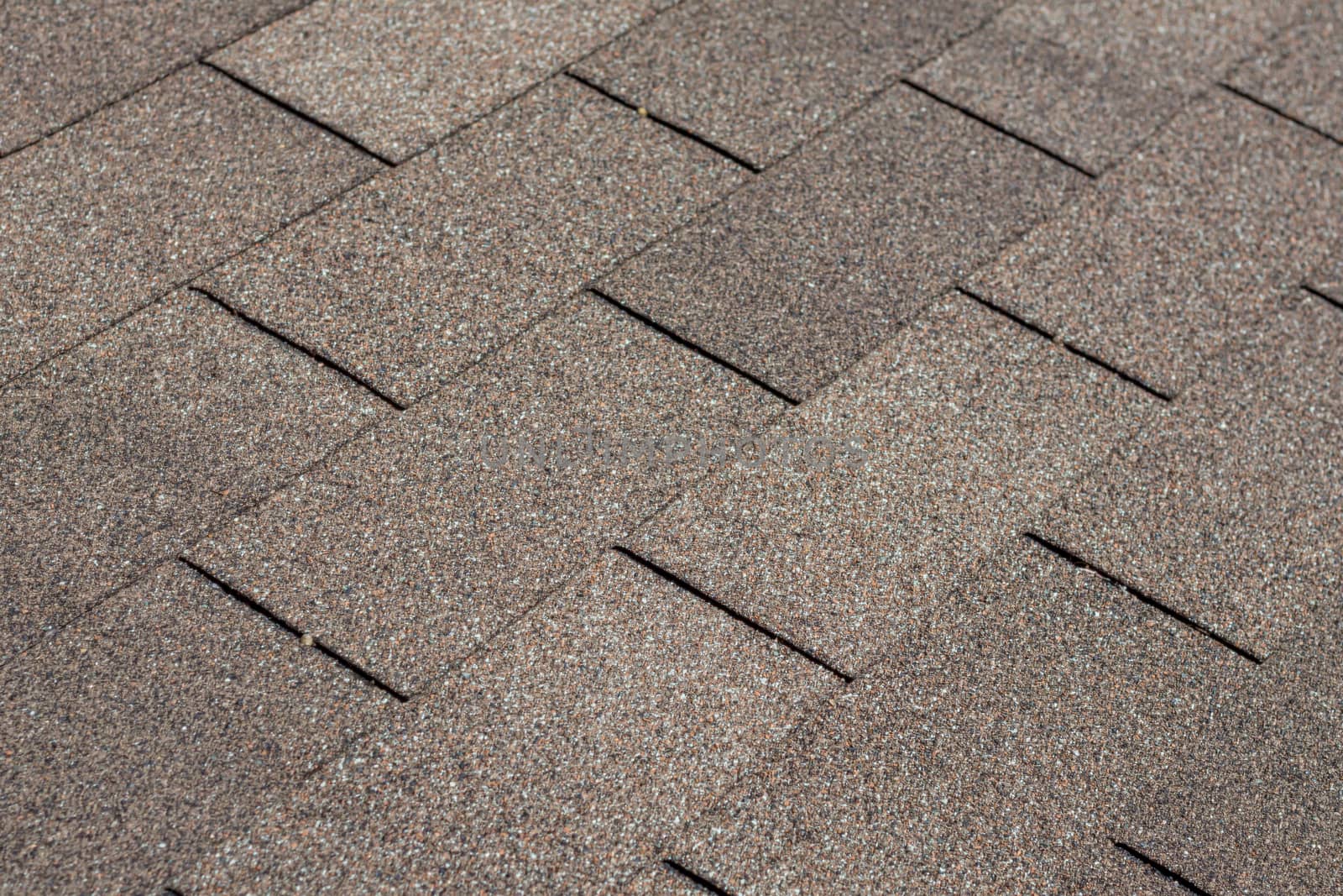 A background image of shingles on a house roof showing their texture, pattern and brown color.