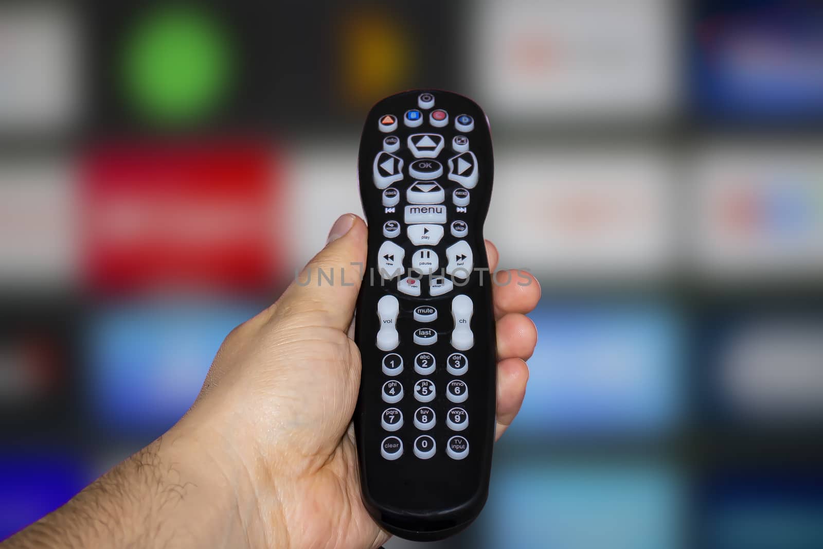 A person holding a control remote with a television screen on the background by oasisamuel