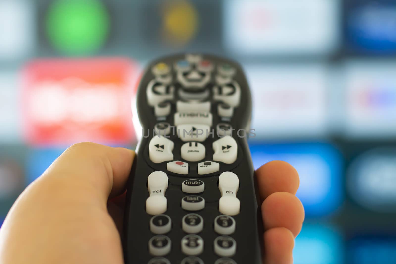 Close up of a person holding a control remote with a television screen on the background by oasisamuel
