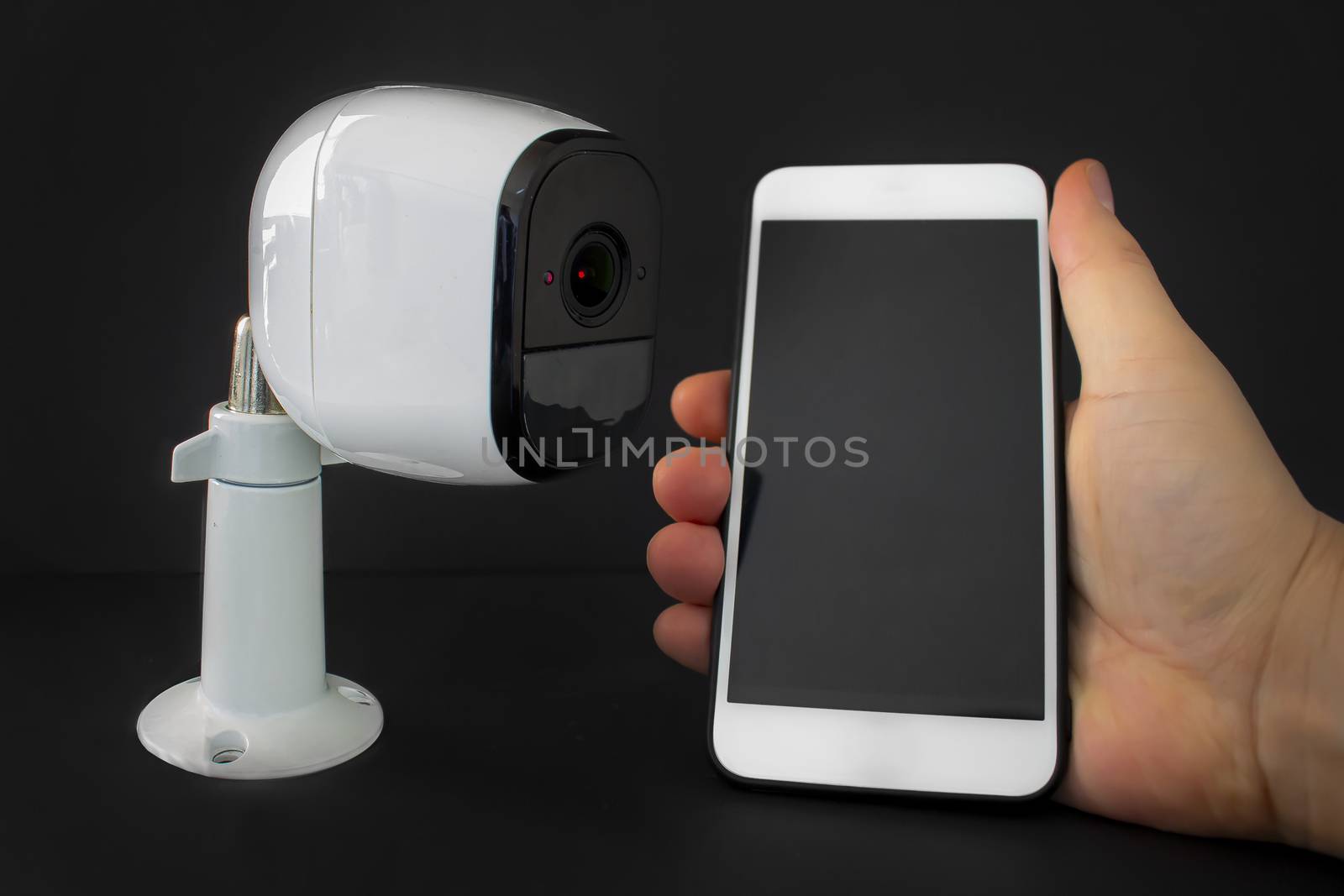A smart security camera with a smart phone hold by a person by oasisamuel