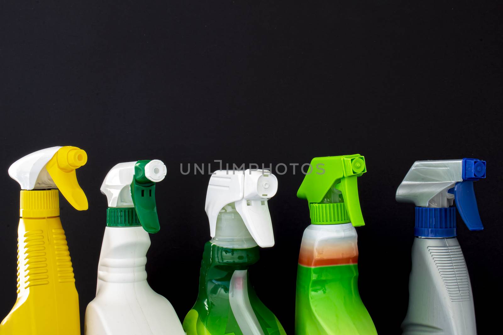 A group of colorful spray cleaners bottles on a black background