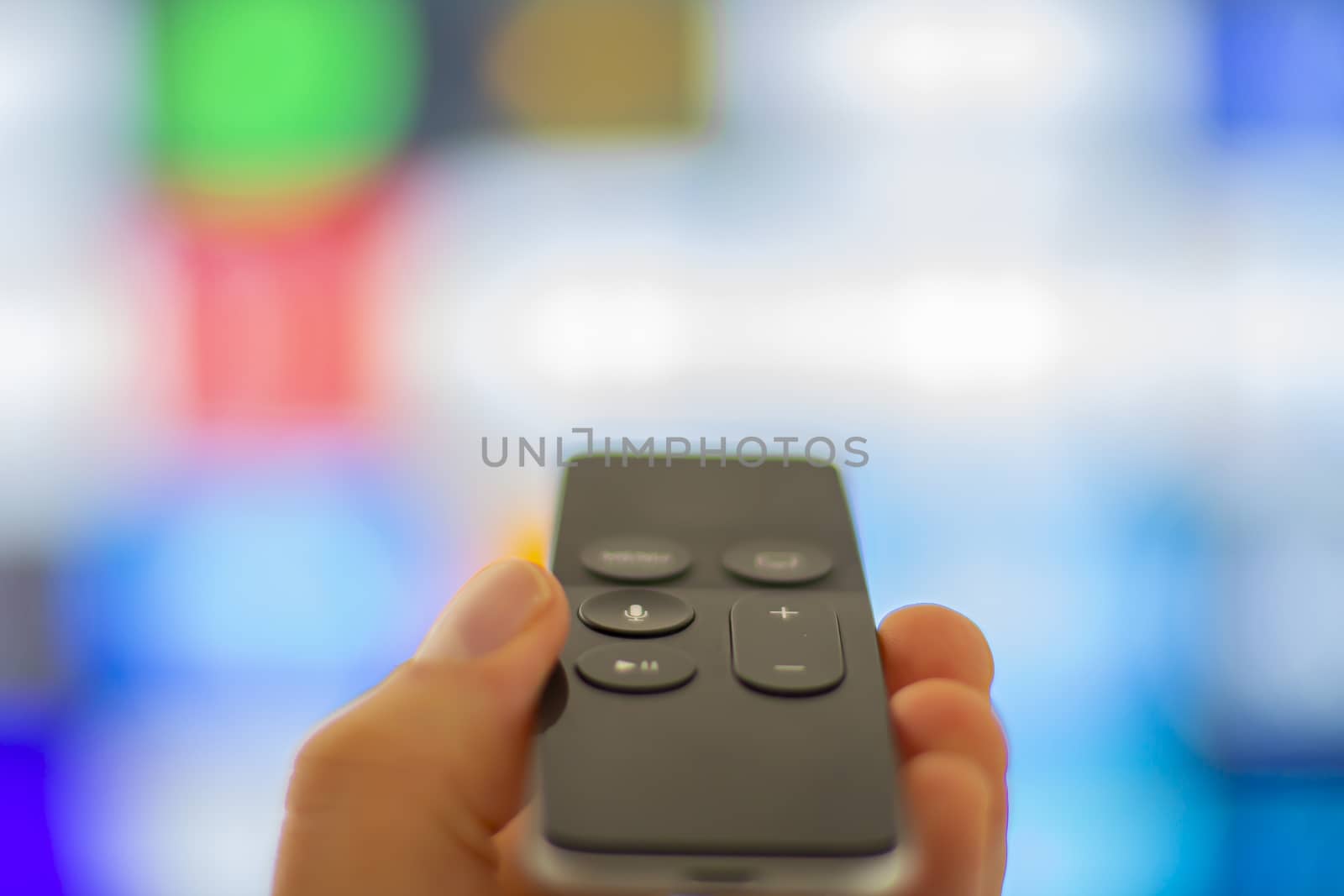 Close up of a person holding a digital media player and microconsole remote with a television screen on the background by oasisamuel