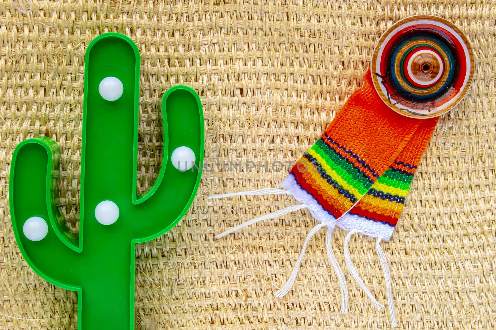 Cinco de Mayo background. A cactus and a sombrero and poncho on a straw rural bag background texture