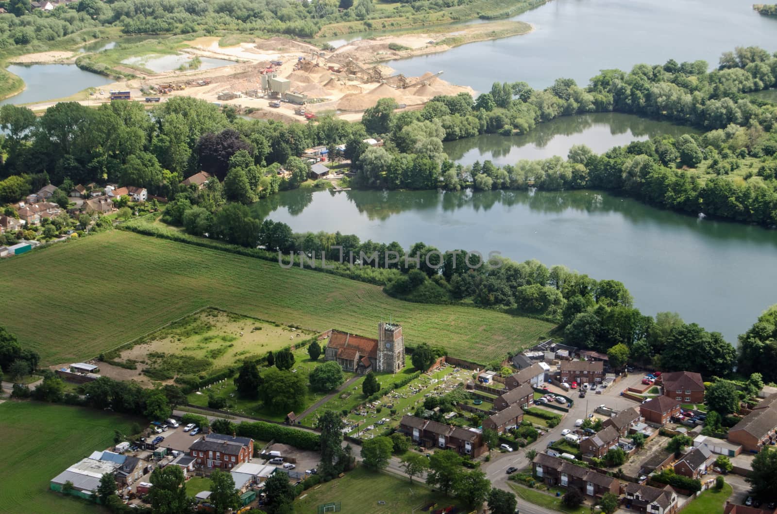 Aerial view on the approach to London's Heathrow Airport of the parish church of St Michael in Horton near Slough in Berkshire.  Beyond the church is the Cemex cement works.