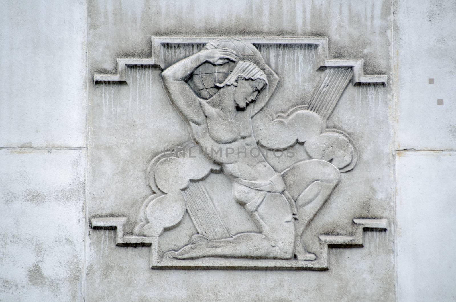 Sculpted stone relief of the Roman hero Atlas, holding the globe on his shoulders.  Exterior of a 1930's building originally constructed as the headquarters of the British Iron and Steel Federation in Westminster, London.  Sculpted by William Aumonier junior in 1937, viewed from public road.