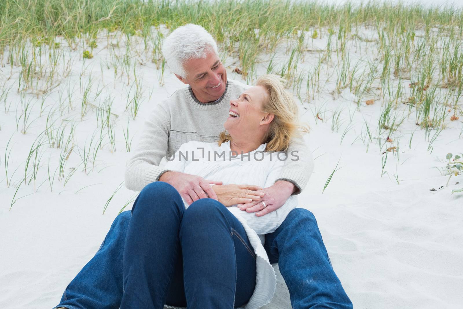 Romantic senior man and woman relaxing on sand at the beach