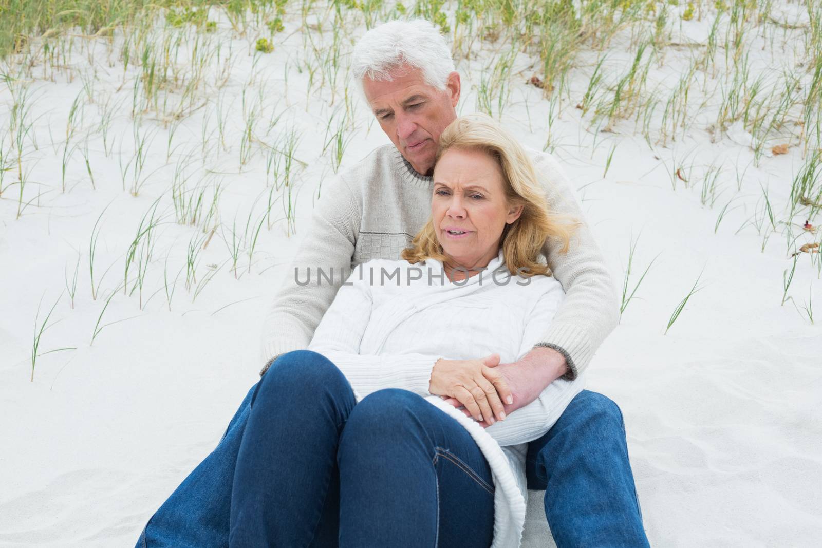 Romantic senior man and woman relaxing on sand at the beach