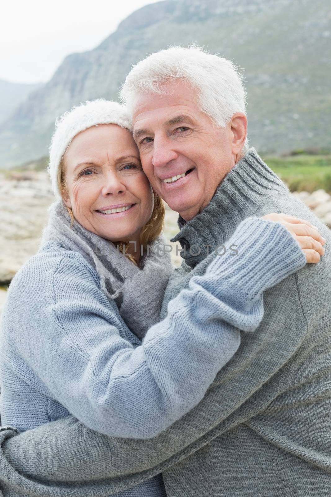 Portrait of a romantic senior couple hugging on a rocky beach