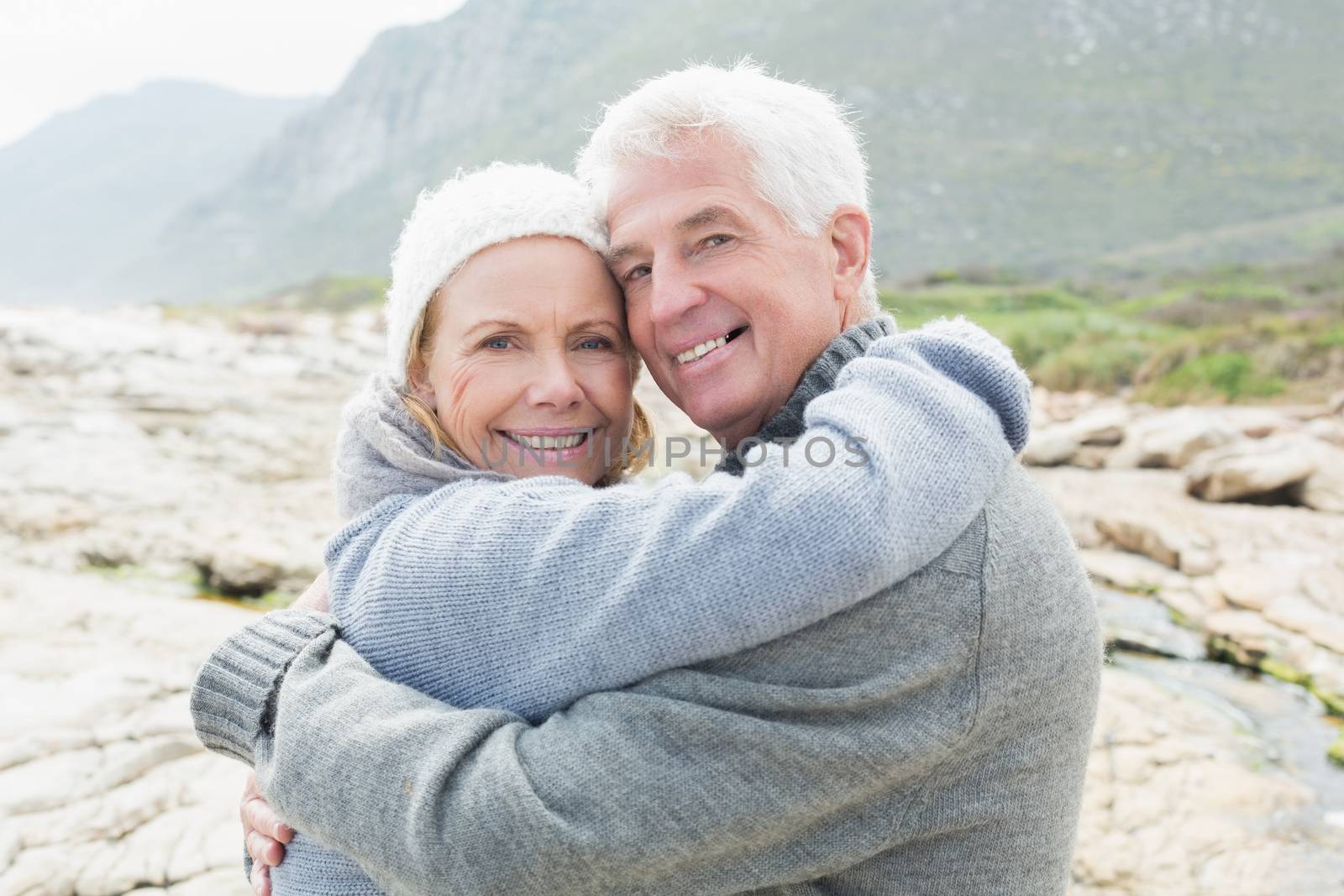 Portrait of a romantic senior couple hugging on a rocky beach