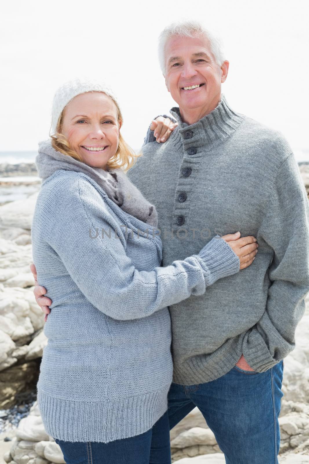 Romantic senior couple standing together on a rocky beach