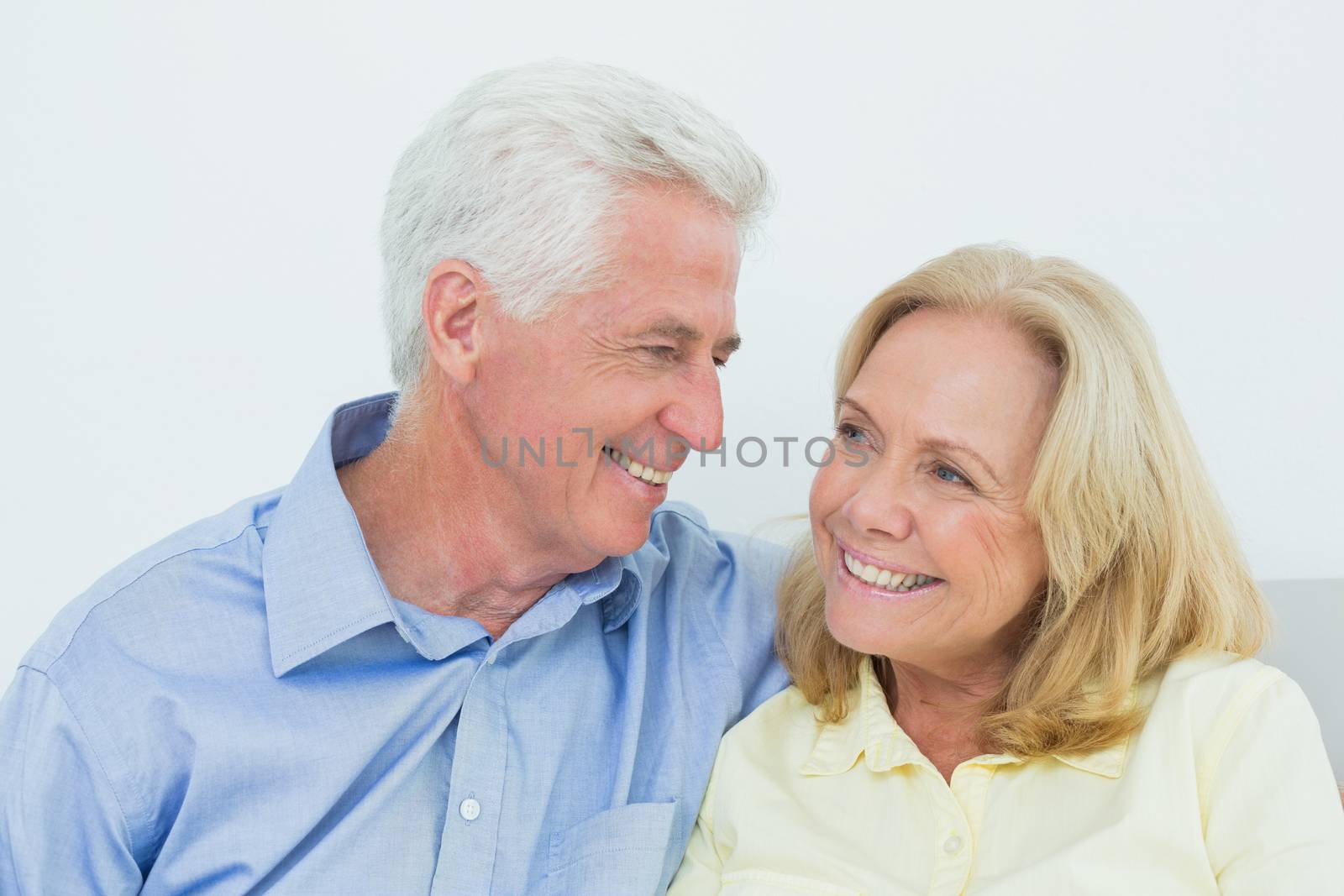 Happy romantic senior couple sitting on sofa in a house