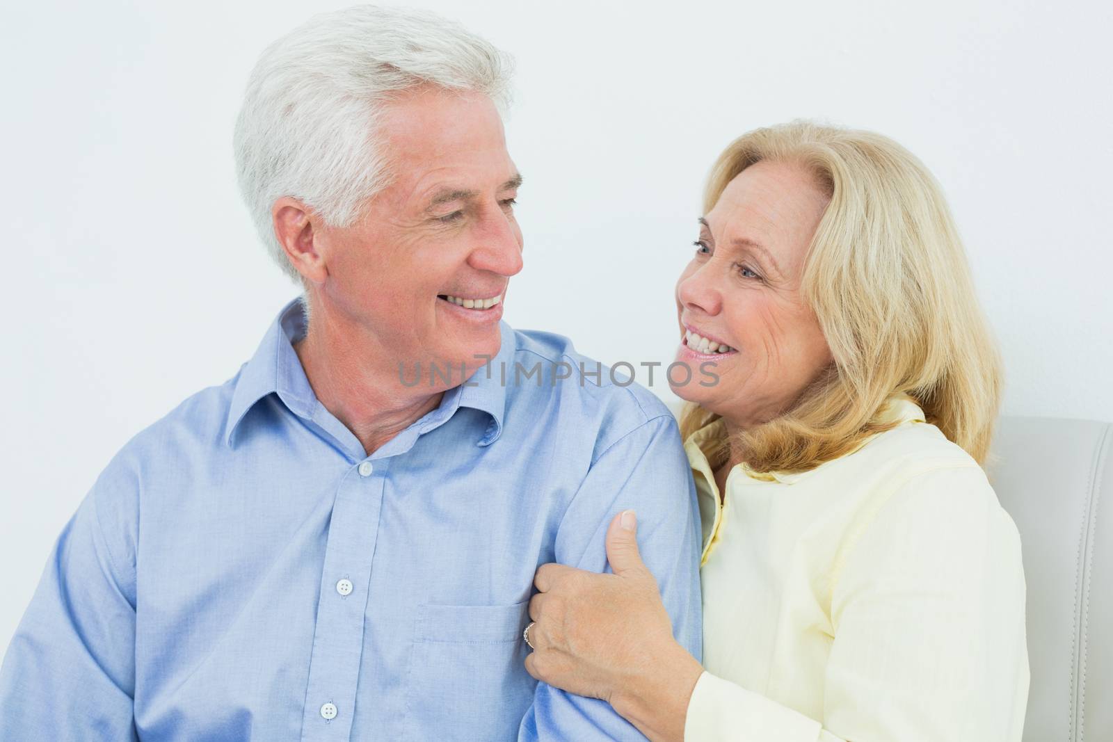 Happy romantic senior couple sitting on sofa in a house