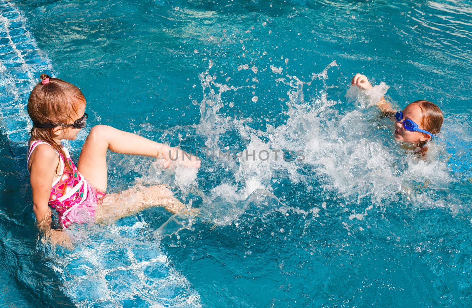 two happy little girls splashing around in the pool