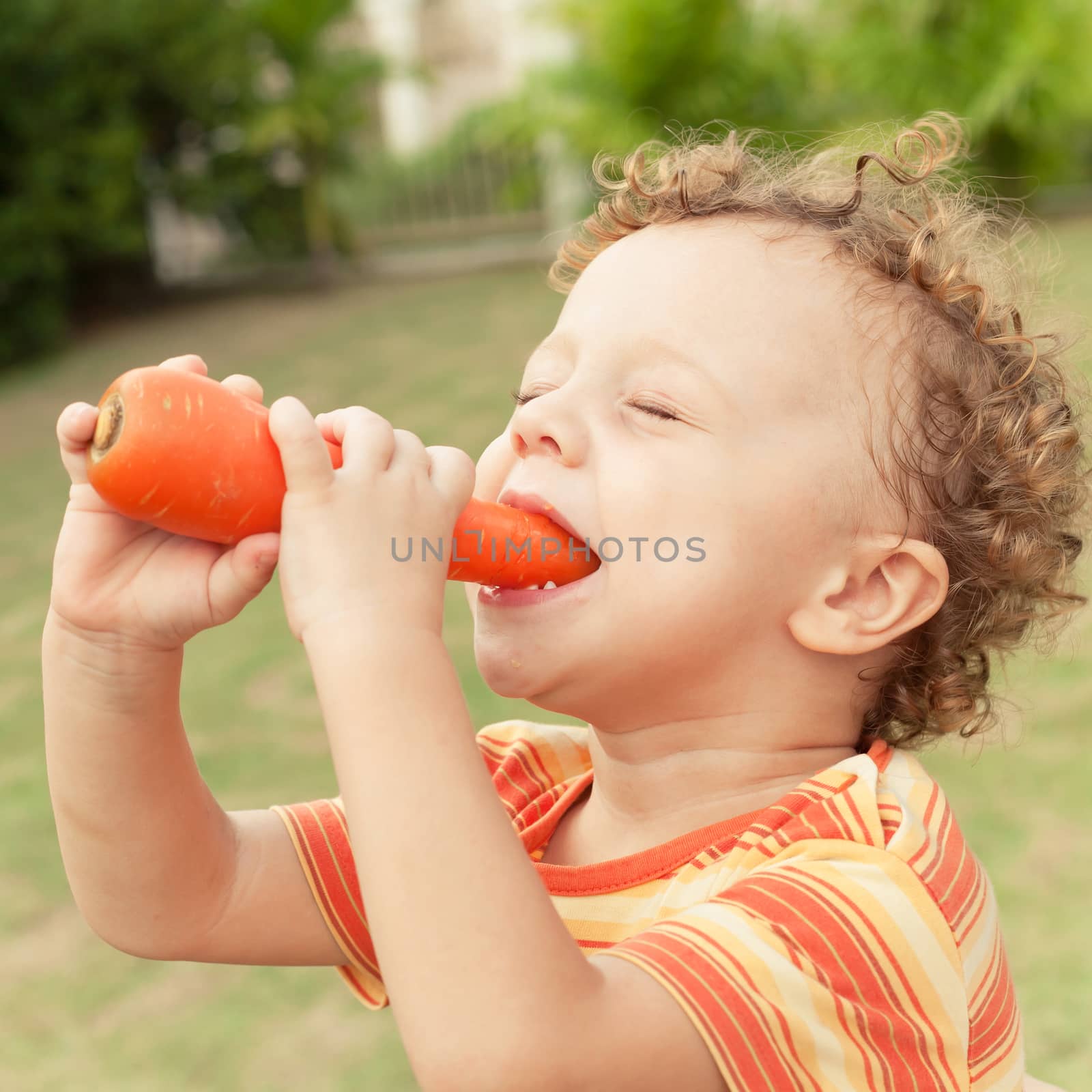 Happy little boy holding a carrots. Concept of healthy food. by altanaka