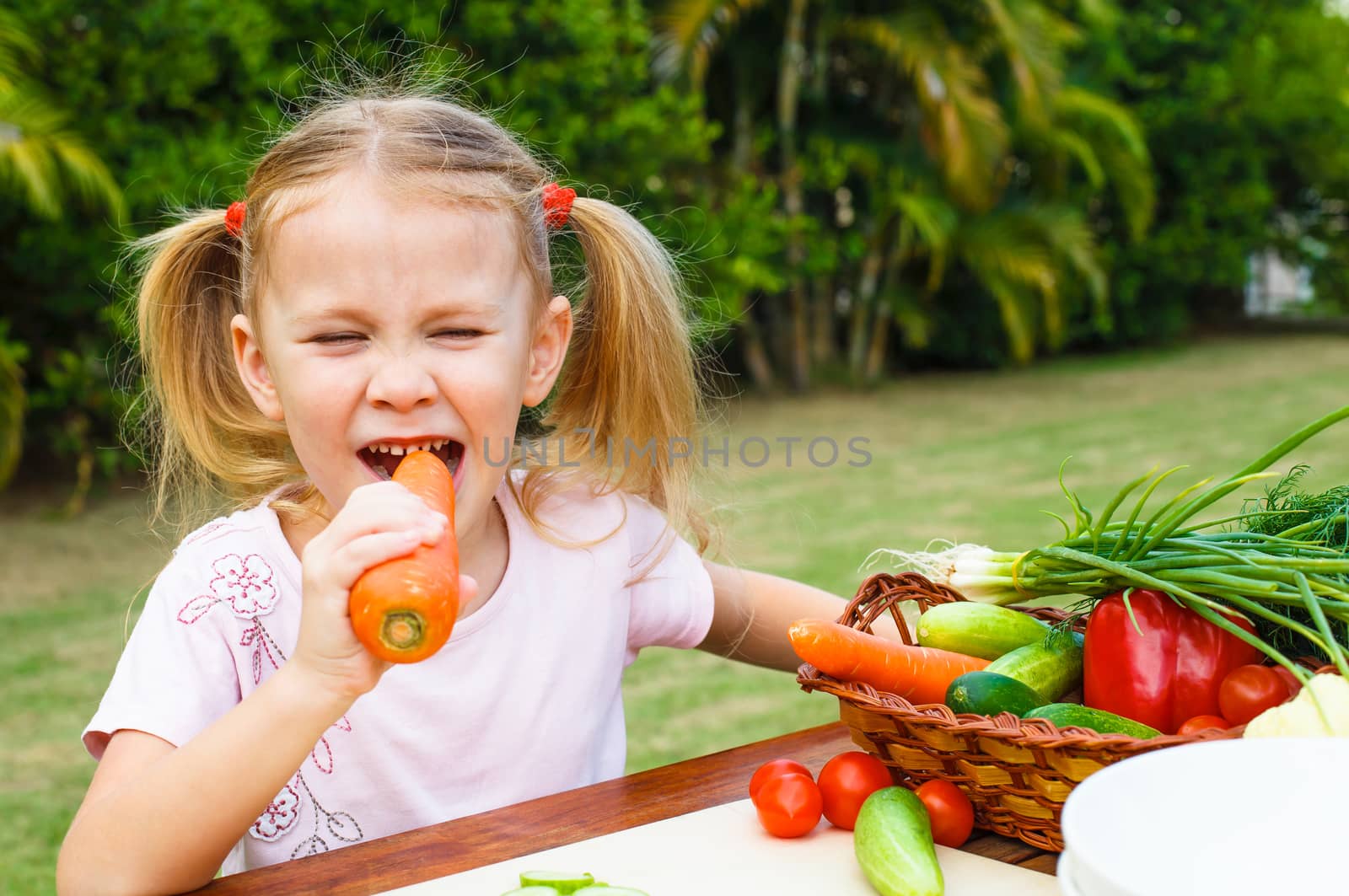 Happy little girl holding a carrots. Concept of healthy food.