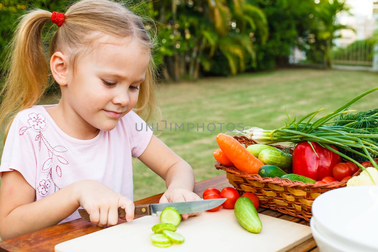 Little girl cutting vegetable for salad. Concept of healthy food by altanaka