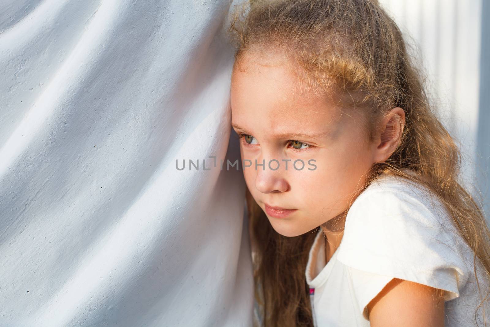 sad little girl on the background of an white wall by altanaka