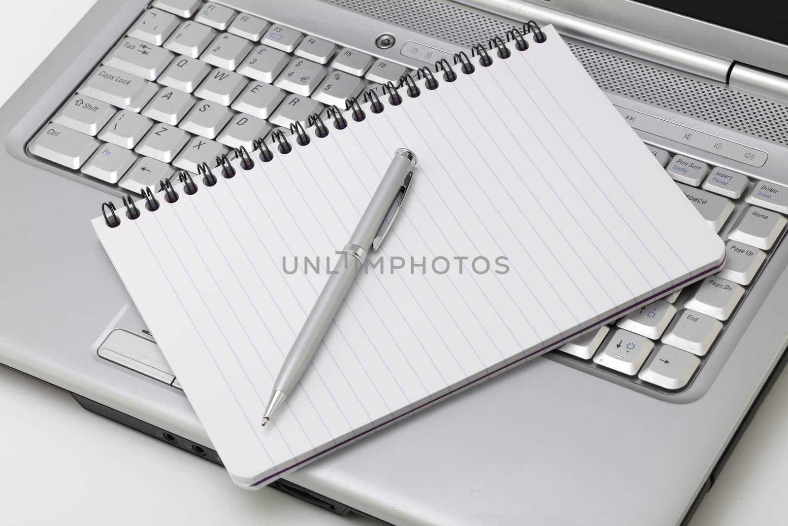 A notebook and pen resting on a laptop PC