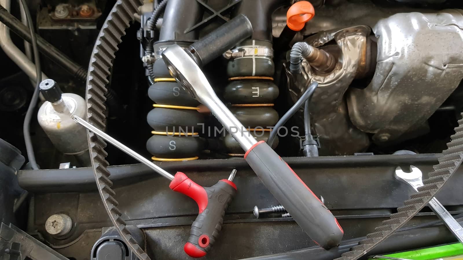 Garage tools on car engine: screw, spanner and ratchet near timing belt
