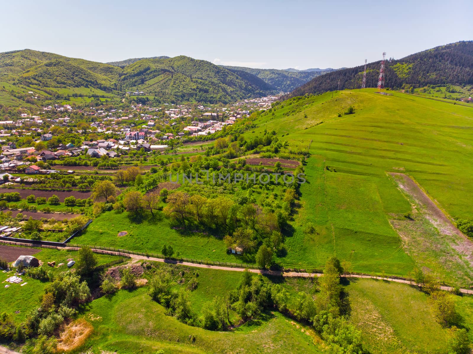 Aerial view of village and forest in springtime: cultivated land, houses and forest from flying drone.