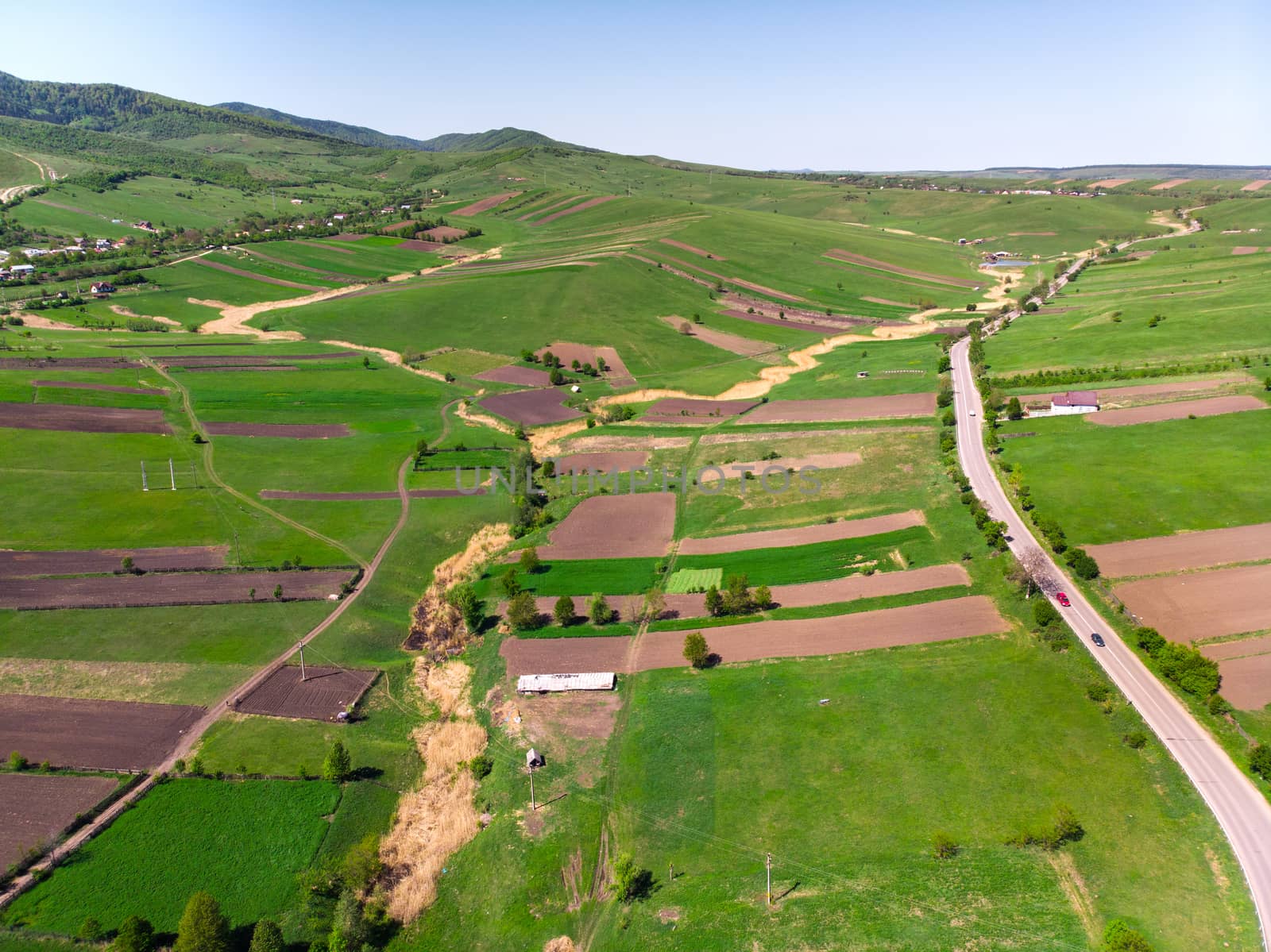 Rural panorama, aerial view: cultivated lands, houses and forest from above