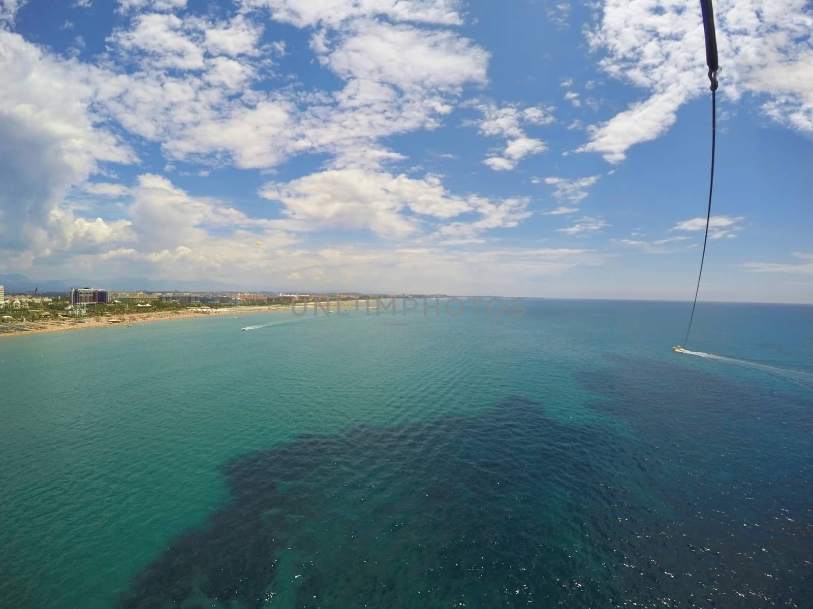 Aerial view of tropical resort during parasailing (speedboat dragging parachute), mediterranean beach in Turkey