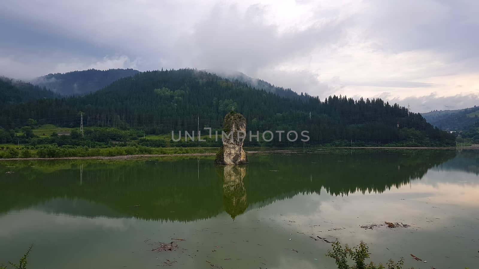 Rock and lake, surrounded by the forest, summer landscape in Romania