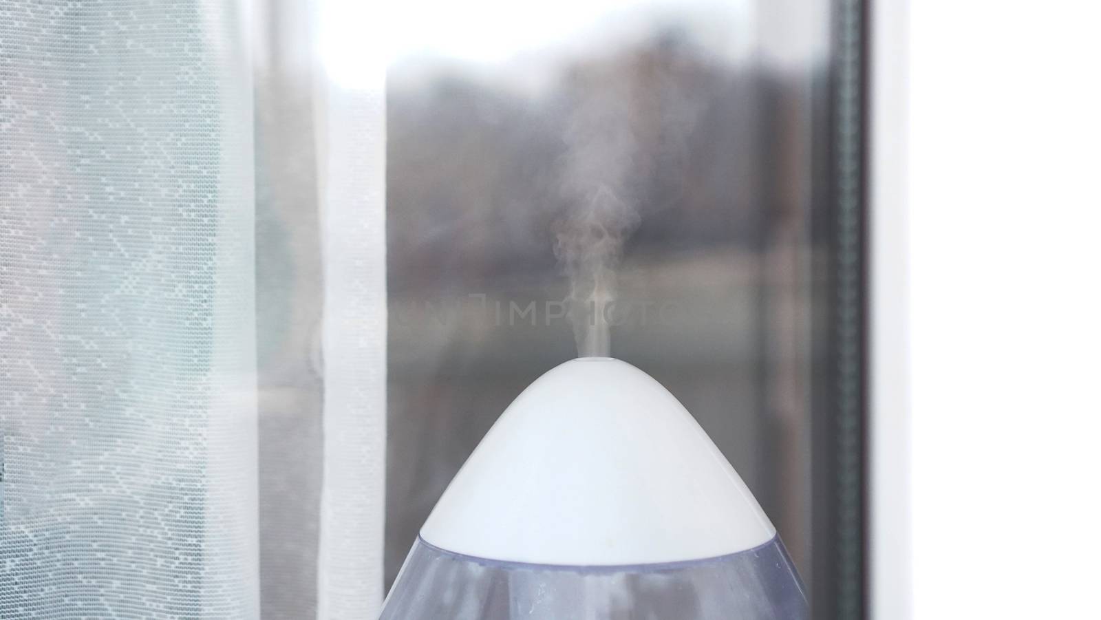 The white ultrasonic humidifier on a window of living room by natali_brill