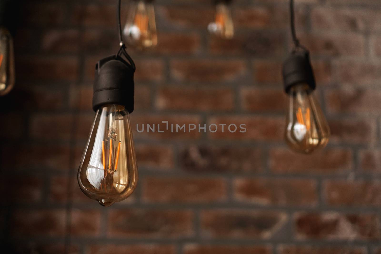 Decorative antique edison style light tungsten bulbs against brick wall background