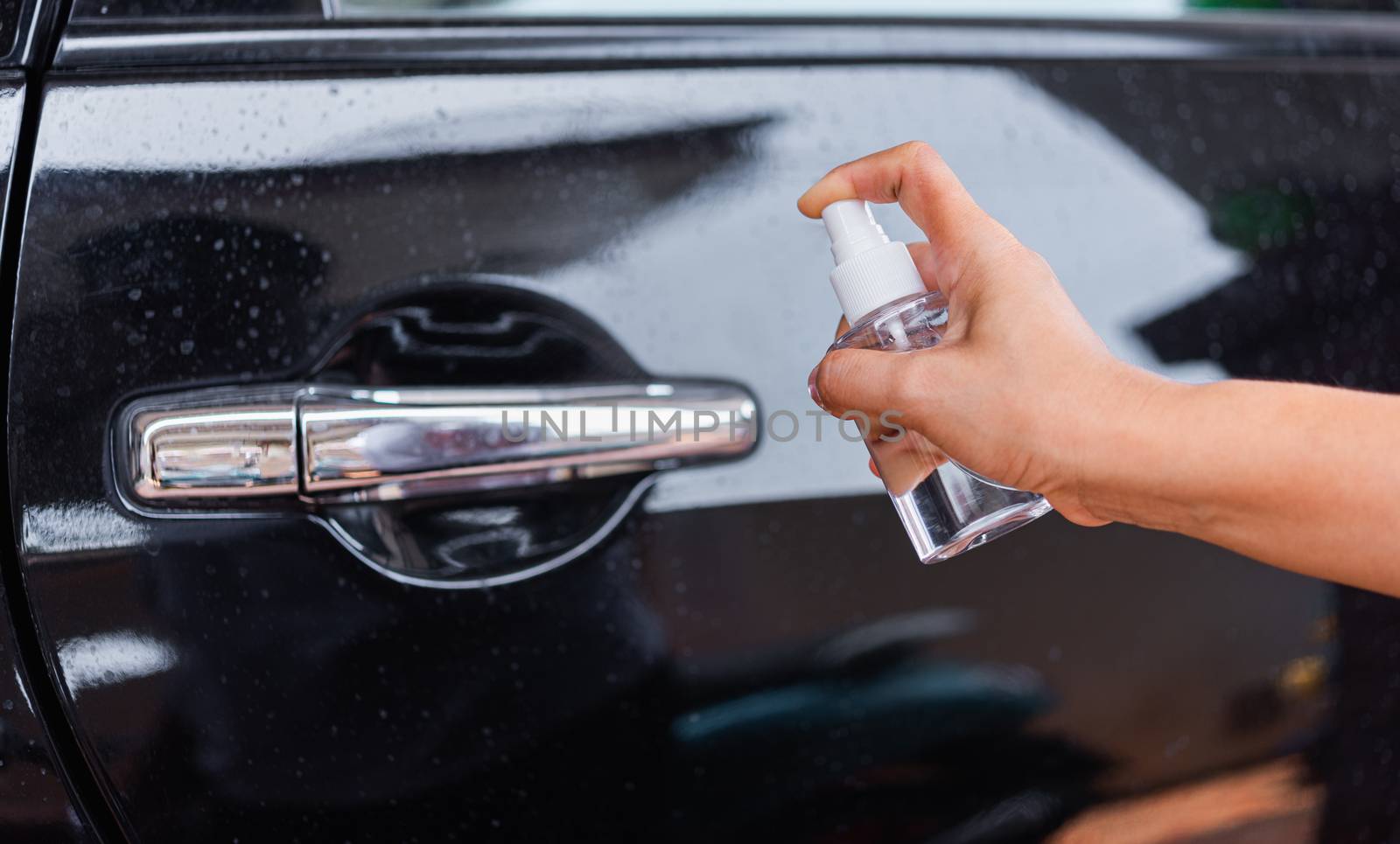Asian young woman applying press dispenser sanitizer alcohol spray squirt to car door wash cleaning, hygiene prevention COVID-19 or coronavirus protection concept, isolated on white background