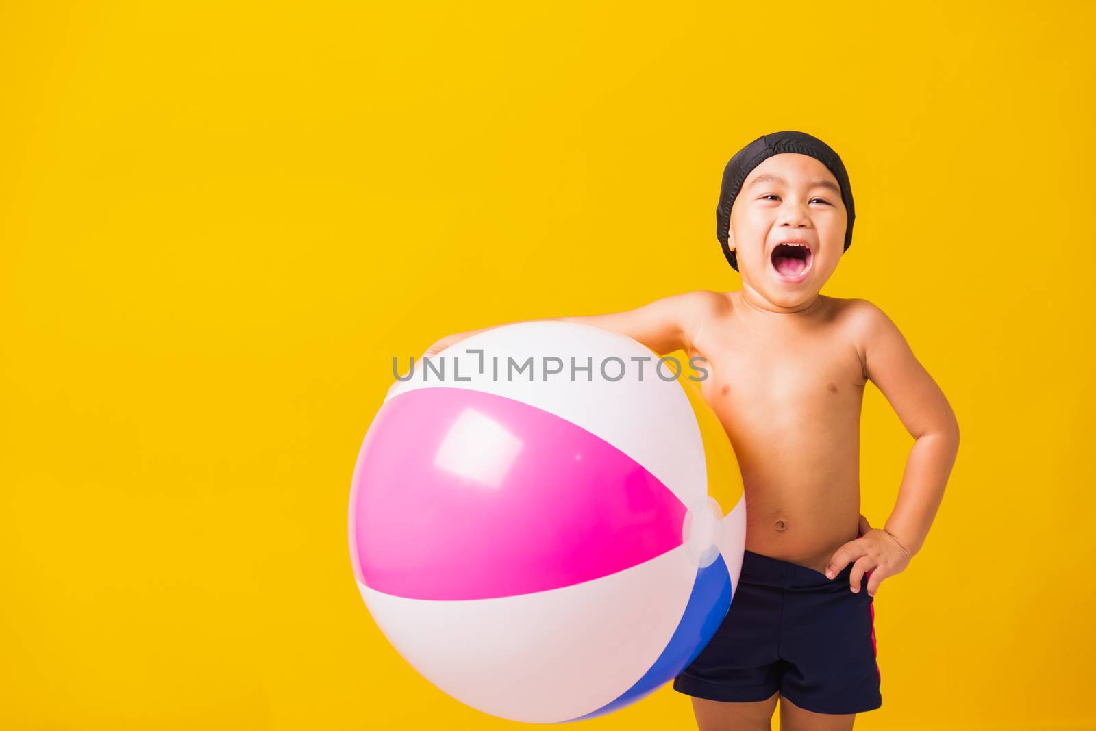 Child boy smiling in swimsuit hold beach ball by Sorapop