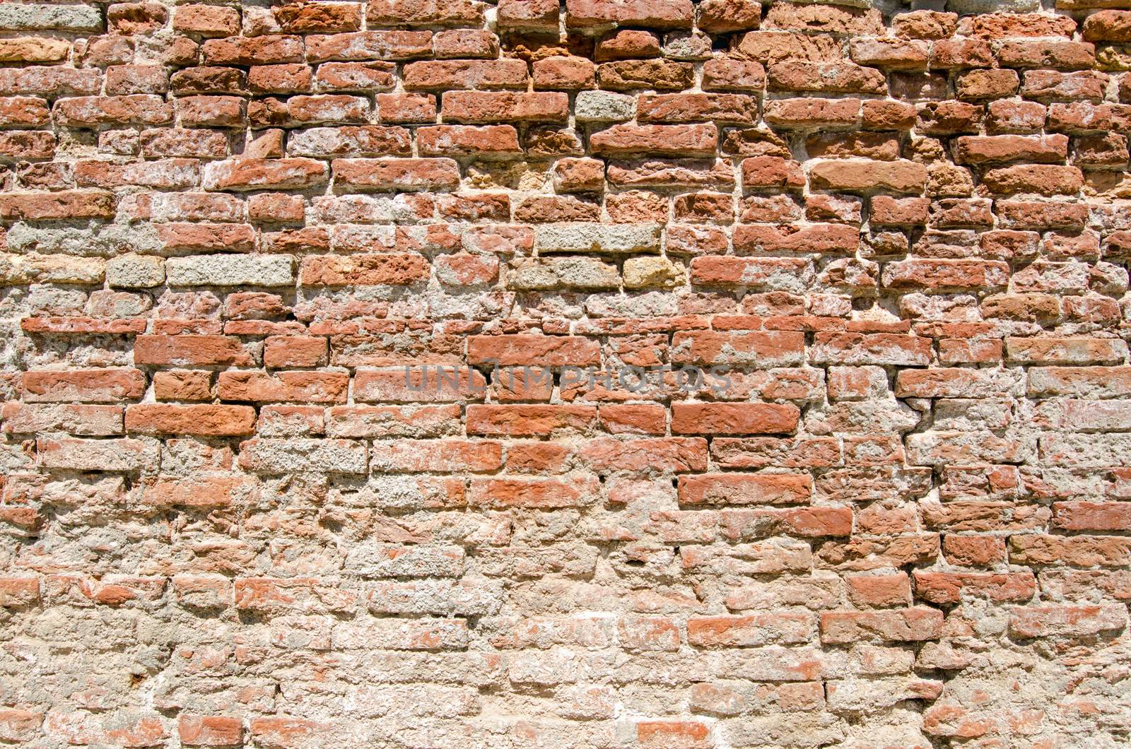 Brick wall with severe weathering and mortar loss on a sunny day in Venice.