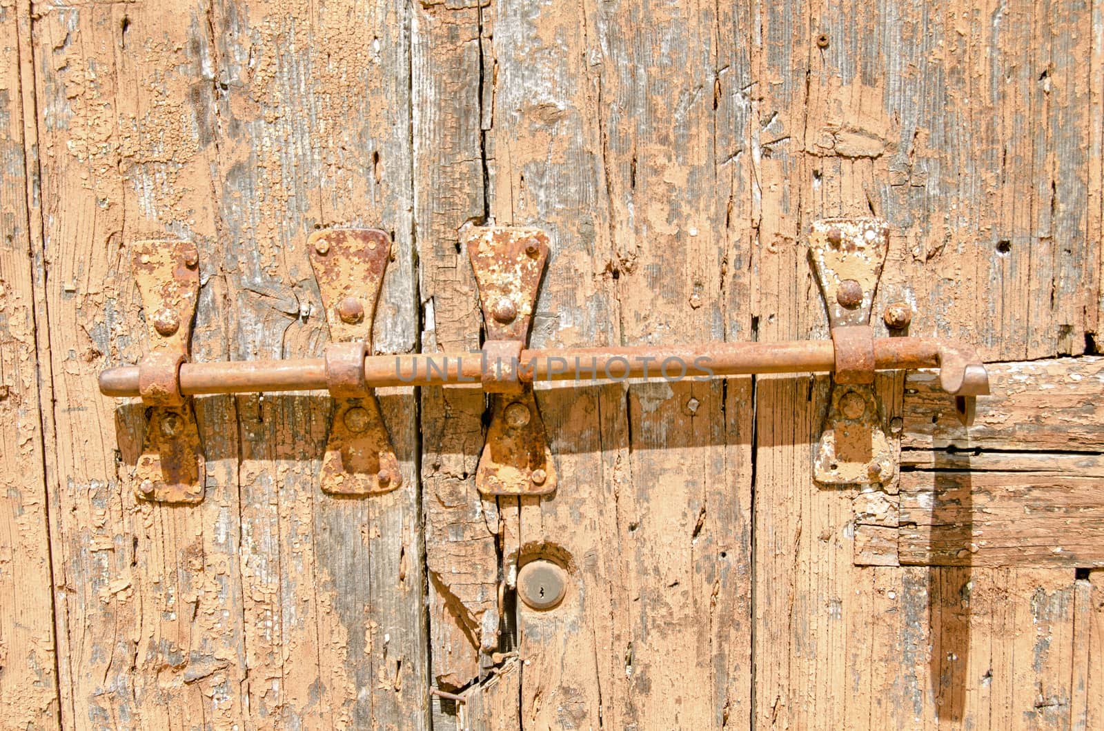 Old wooden door with peeling paint bolted shut.