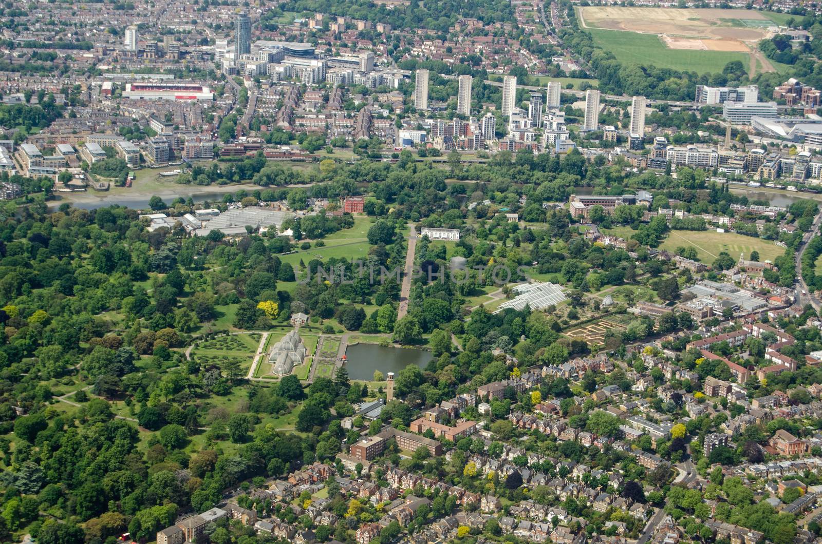 Aerial view of the historic Royal Botanic Gardens at Kew in West London on a sunny summer day.  The Palm House is in the middle of the image with Brentford Football Club's stadium to the top left.  