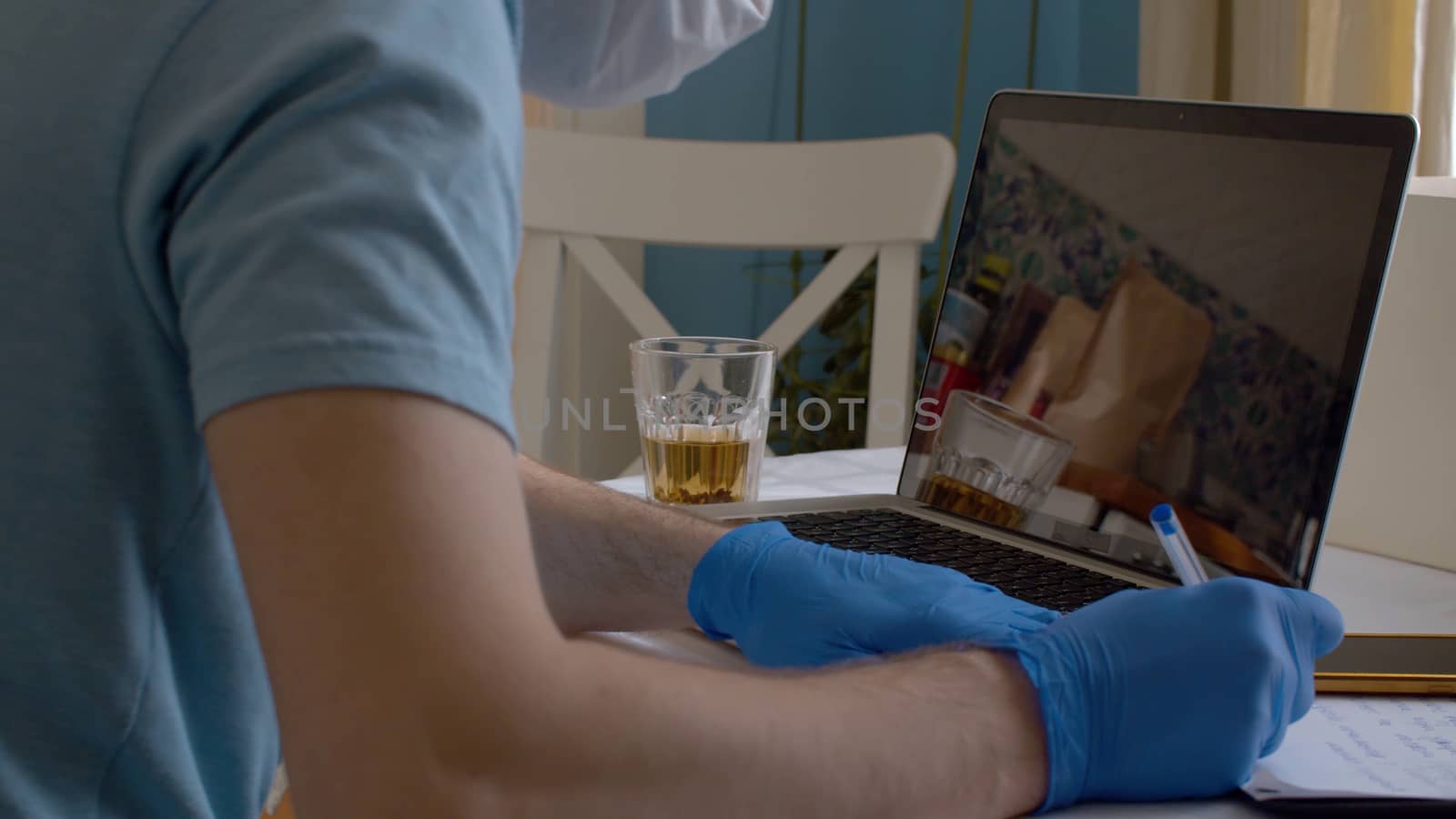 Close up hands of young man in protective gloves writing something on the paper. Home office. Remote job. Coronavirus epidemic