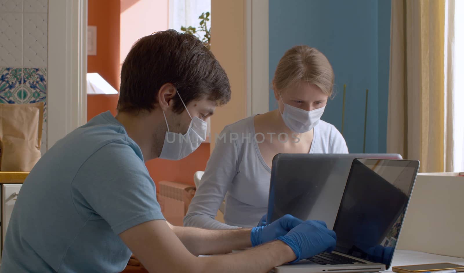 Nice couple working from home on computers in bright kitchen. Remote work during quarantine, coronavirus epidemic.