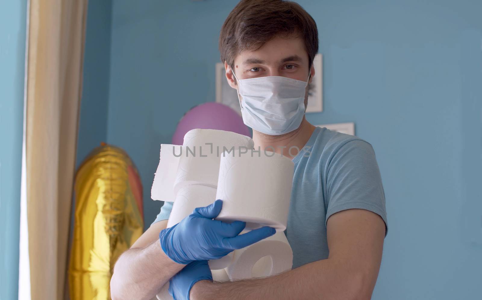 Coronavirus panic buying humor. Funny man holding many rolls of toilet paper, he bought in connection with the epidemic. Covid-19 pandemic, quarantine