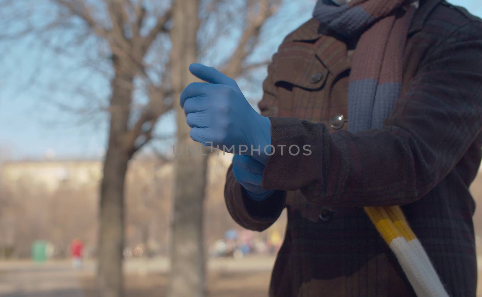 Close up hands of a young man putting on a protective gloves outdoors in the city. Protect yourself and your loved ones. Covid-19 pandemic