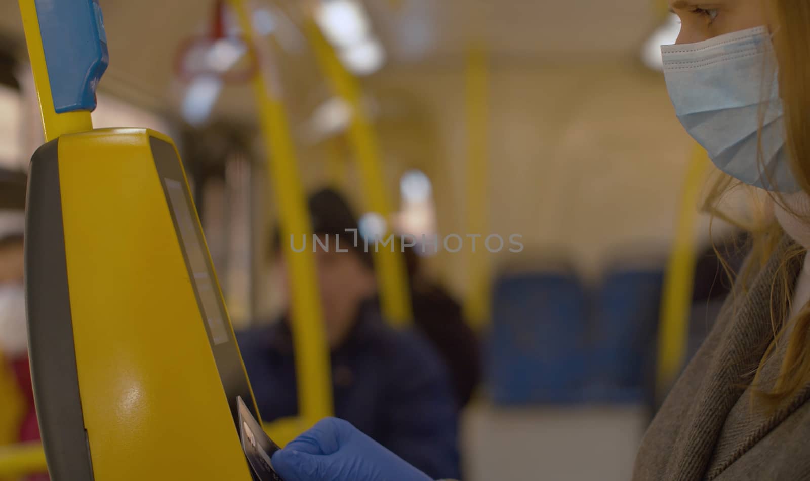 Woman in mask and gloves paying in the bus by Alize
