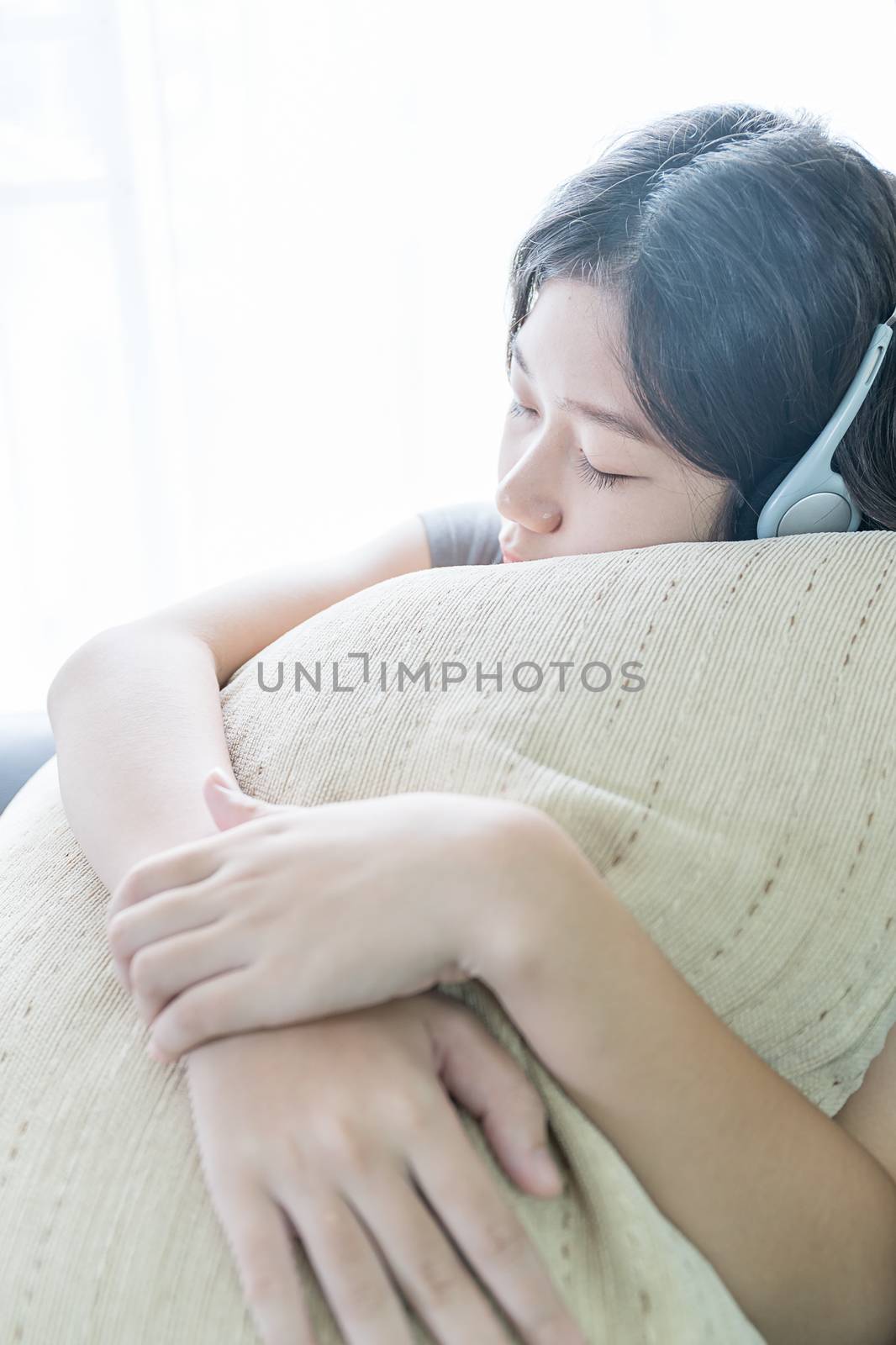 Close up young asian woman short hair listening music on the couch at home