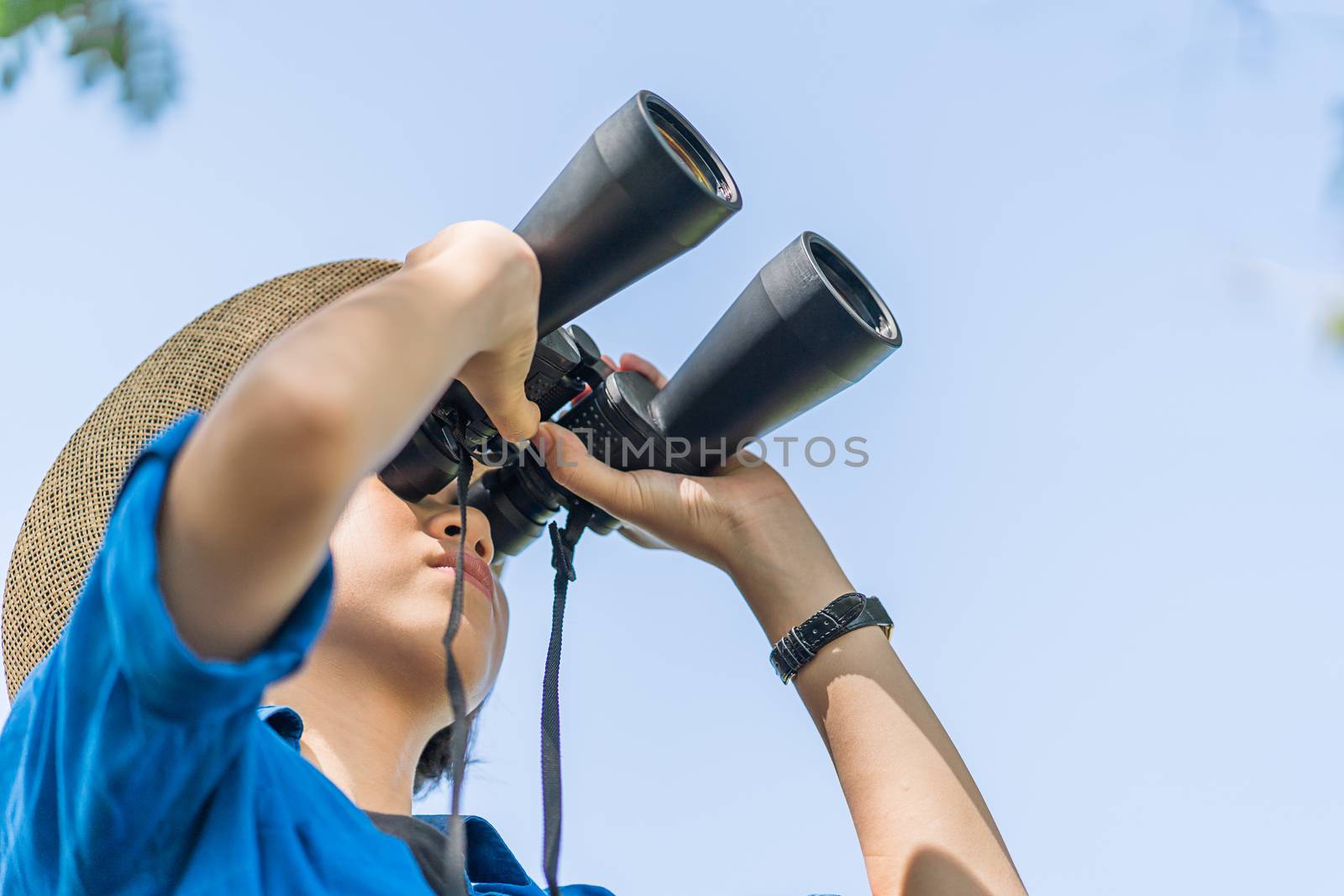 Close up Young asian woman short hair wear hat and hold binocular in grass field countryside Thailand