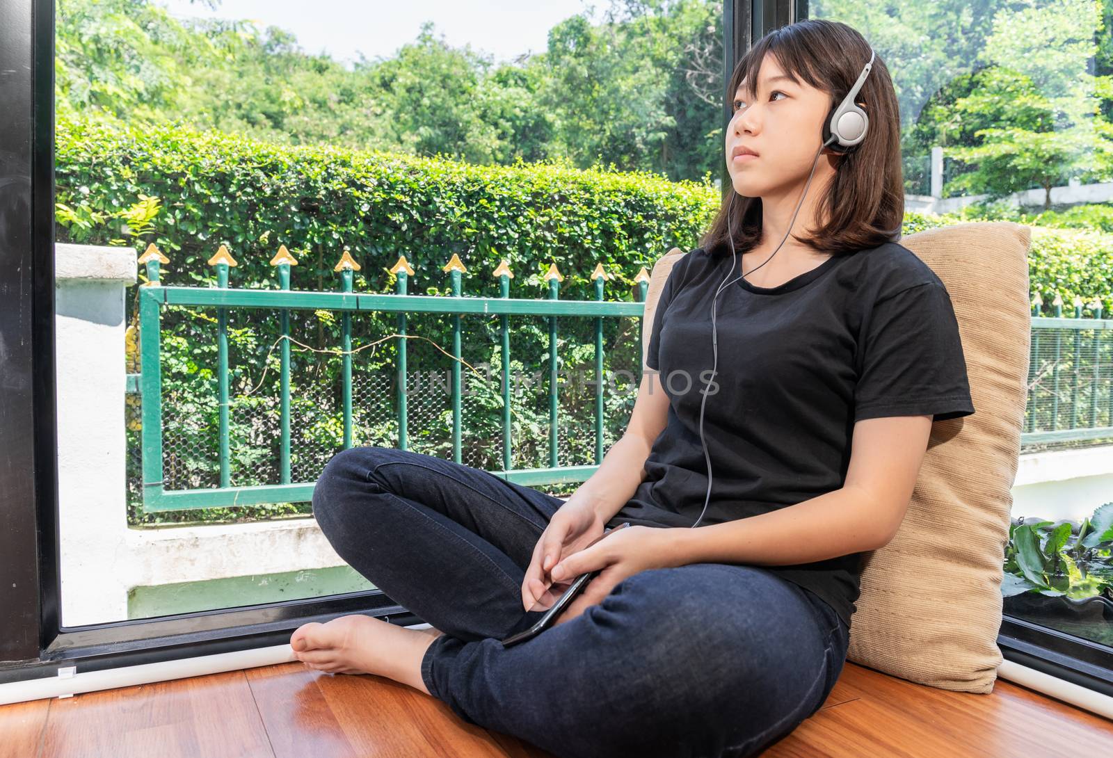 Happy teenage female  learning to the music from smartphone in room at home